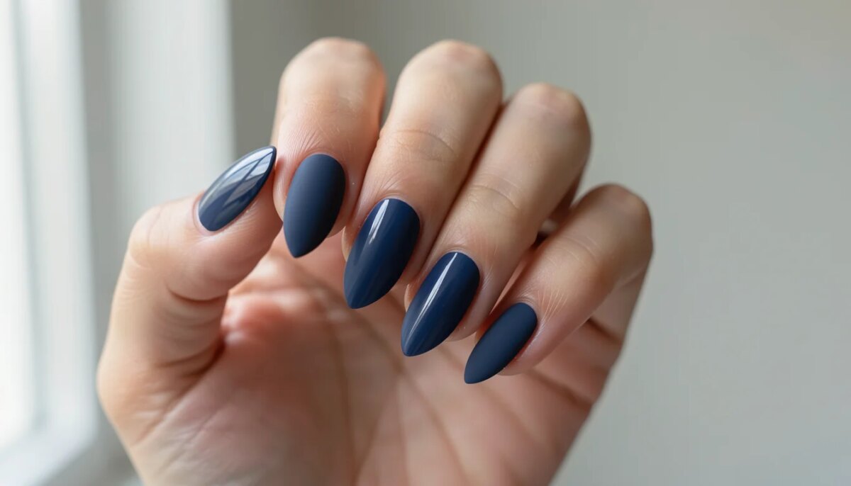 Mão feminina com unhas curtas em gel azul marinho fosco, acabamento impecável, luz natural suave.